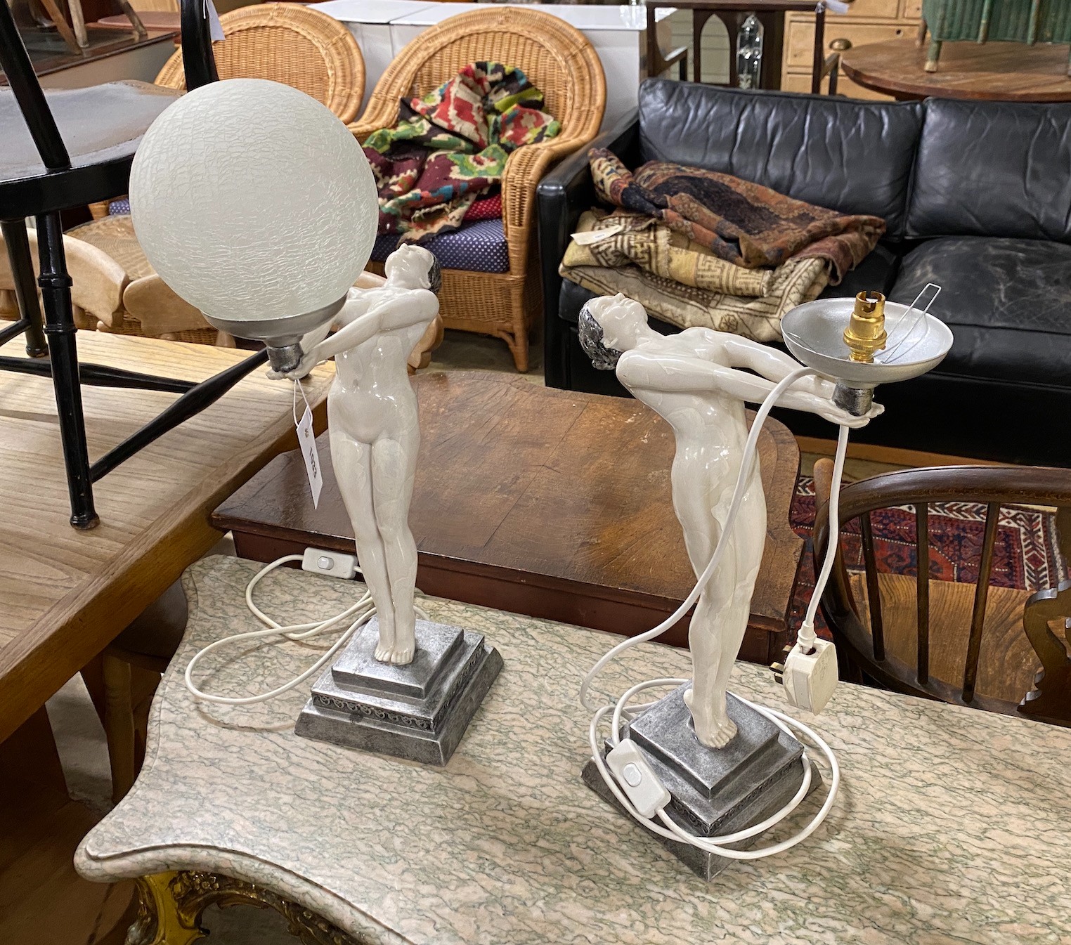 A pair of Art Deco style resin figural lights (lacking one globe), height 55cm